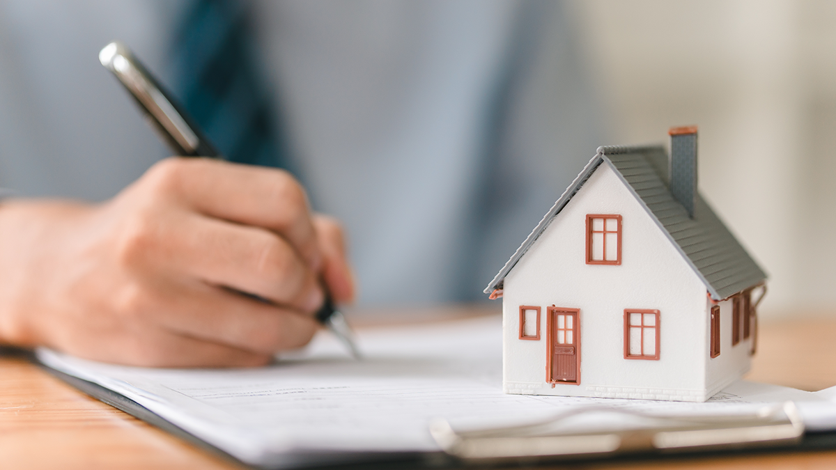 Man signing contract with house