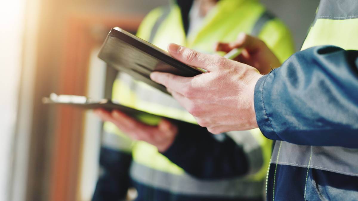 A picture of two workers with a clipboard and IPad