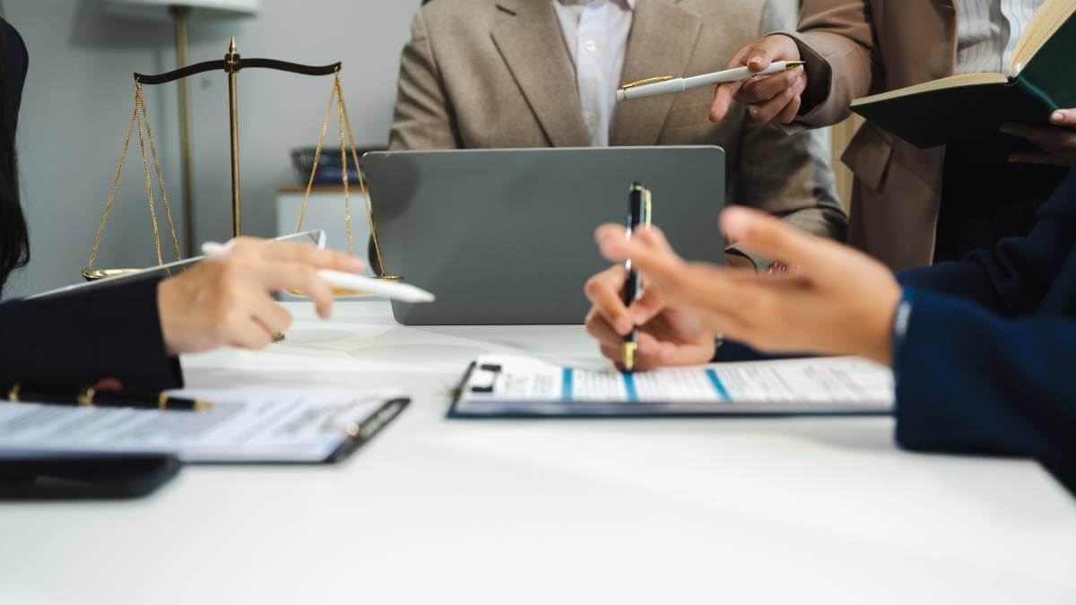 people around a table with documents and laptop